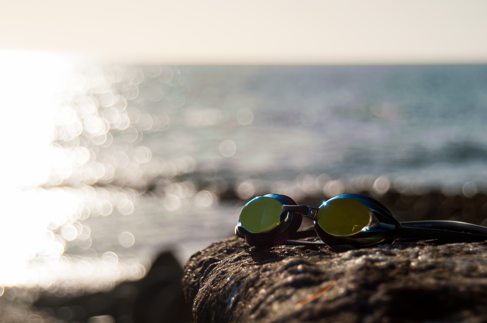 A pair of swim goggles pictured in front of ocean